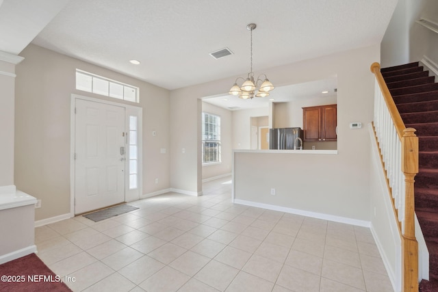 tiled foyer entrance with a chandelier and a textured ceiling