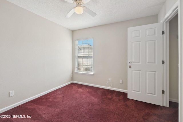 spare room featuring ceiling fan, dark carpet, and a textured ceiling