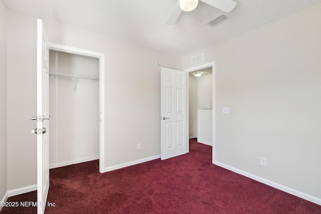 unfurnished bedroom featuring dark colored carpet, ceiling fan, and a closet