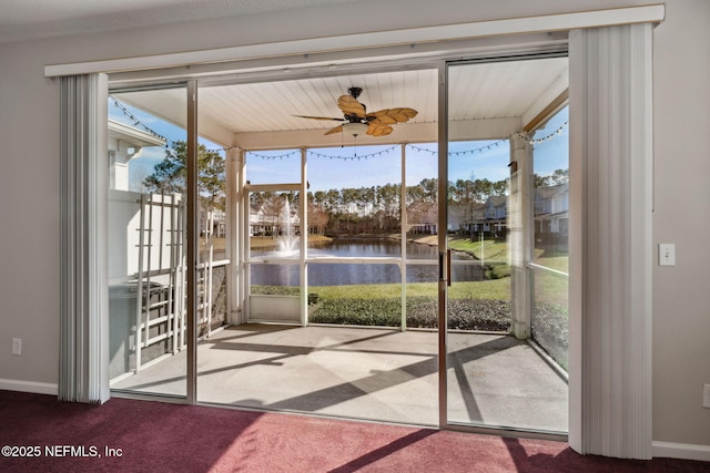 unfurnished sunroom featuring a water view and ceiling fan