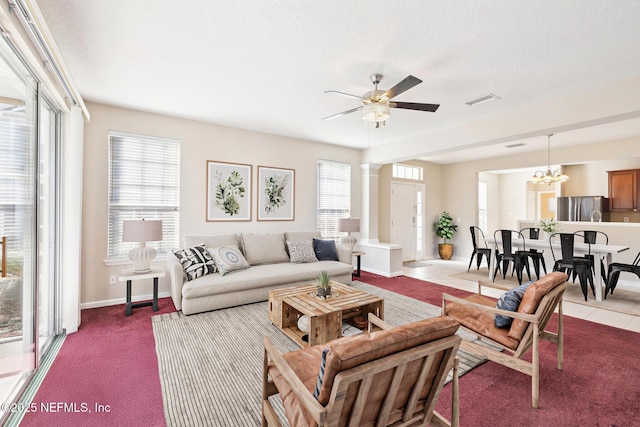 carpeted living room with decorative columns, ceiling fan with notable chandelier, and a textured ceiling