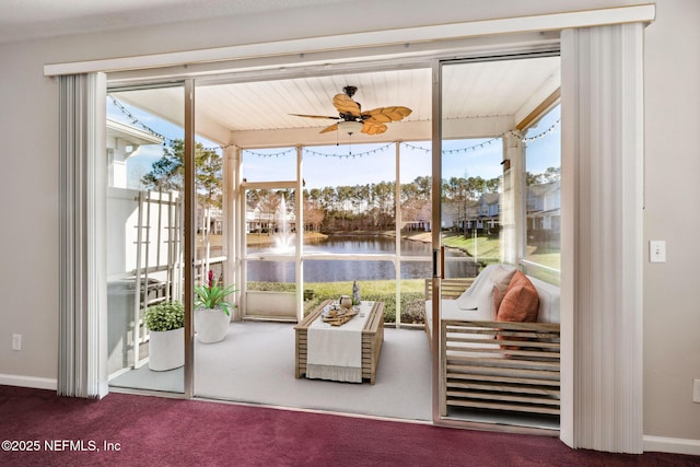 unfurnished sunroom featuring ceiling fan and a water view