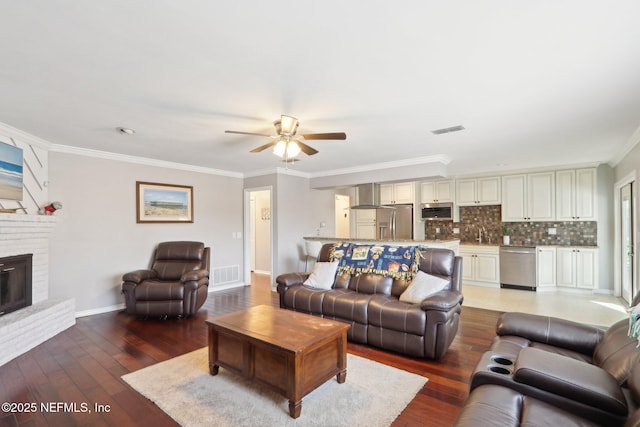 living room with crown molding, sink, hardwood / wood-style flooring, and a fireplace