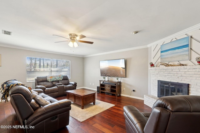 living room with crown molding, a brick fireplace, ceiling fan, and dark hardwood / wood-style flooring