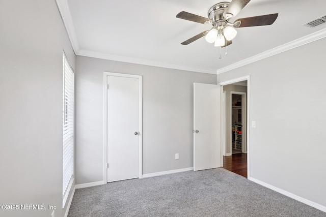 unfurnished bedroom with dark carpet, ornamental molding, and ceiling fan