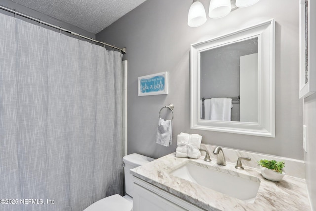 bathroom with vanity, toilet, and a textured ceiling