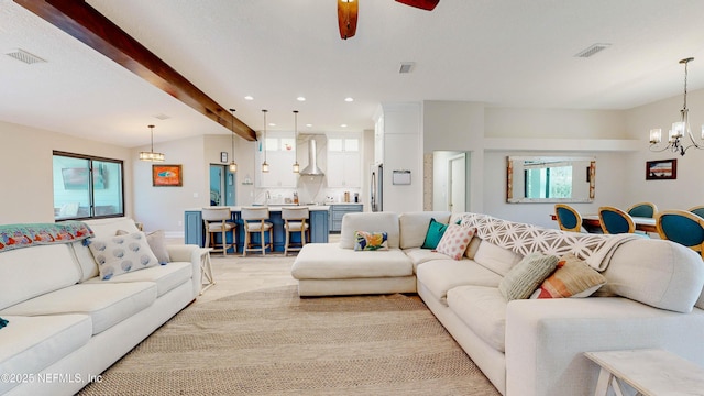 living area featuring ceiling fan with notable chandelier, visible vents, beamed ceiling, and recessed lighting