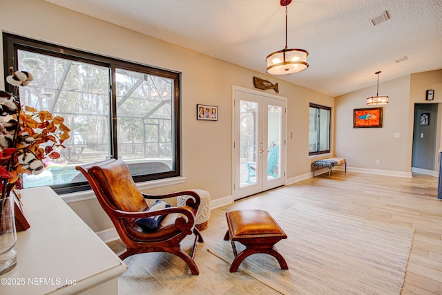 interior space with visible vents, lofted ceiling, a textured ceiling, french doors, and light wood-type flooring