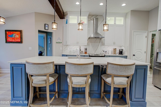 kitchen featuring backsplash, white cabinetry, a sink, wall chimney range hood, and stainless steel fridge with ice dispenser