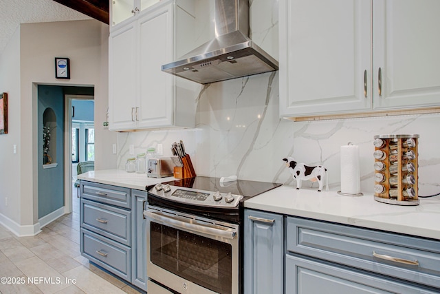 kitchen with stainless steel range with electric stovetop, white cabinets, wall chimney exhaust hood, and tasteful backsplash