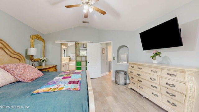 bedroom featuring a barn door, visible vents, ceiling fan, vaulted ceiling, and light wood-type flooring