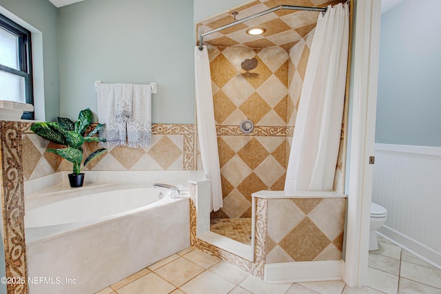 full bathroom featuring a wainscoted wall, toilet, a stall shower, tile patterned flooring, and a bath