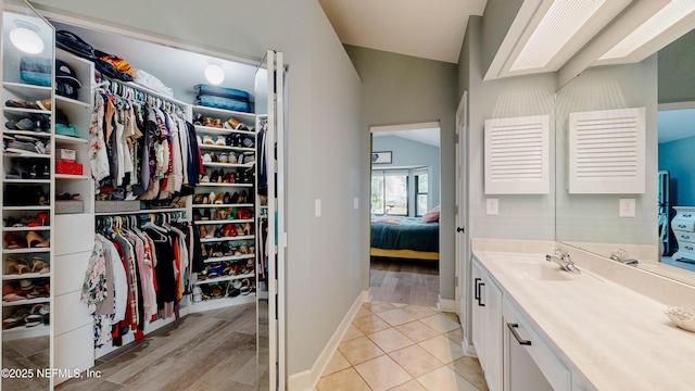 bathroom featuring vaulted ceiling with skylight, baseboards, tile patterned floors, a spacious closet, and vanity