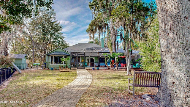 exterior space featuring a lanai, a fenced backyard, a chimney, and a front lawn