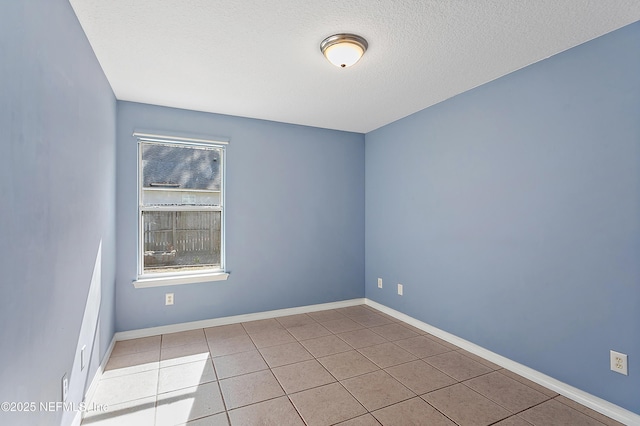 spare room featuring a textured ceiling and light tile patterned floors