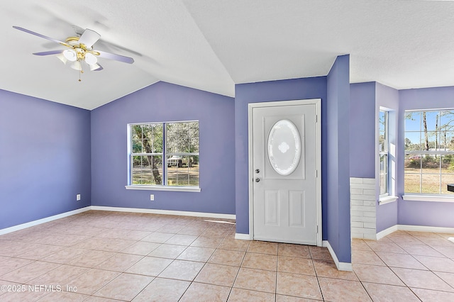 entrance foyer featuring light tile patterned floors, a textured ceiling, vaulted ceiling, and ceiling fan