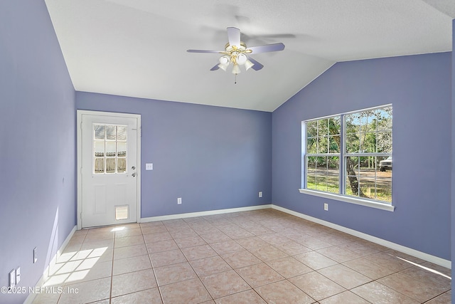 tiled empty room with vaulted ceiling and ceiling fan