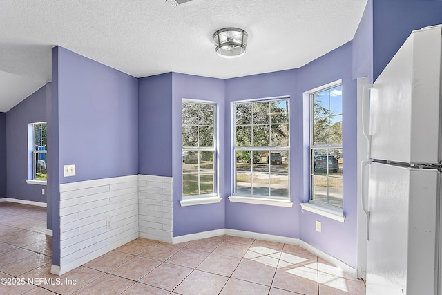 tiled empty room with a textured ceiling