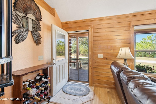 entryway featuring lofted ceiling, wooden walls, and light wood-type flooring