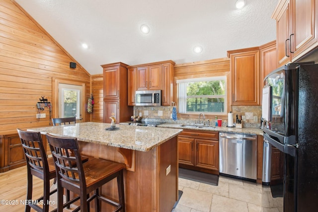 kitchen with lofted ceiling, sink, appliances with stainless steel finishes, tasteful backsplash, and a kitchen island