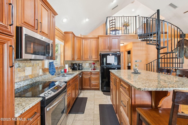 kitchen featuring a breakfast bar, sink, appliances with stainless steel finishes, a kitchen island, and light stone countertops