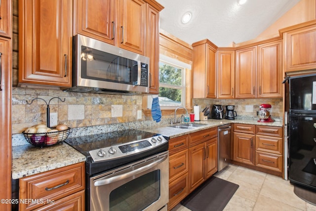 kitchen featuring sink, stainless steel appliances, light stone counters, tasteful backsplash, and vaulted ceiling