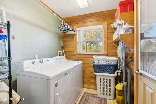 laundry room with wooden walls, a textured ceiling, and washer and clothes dryer