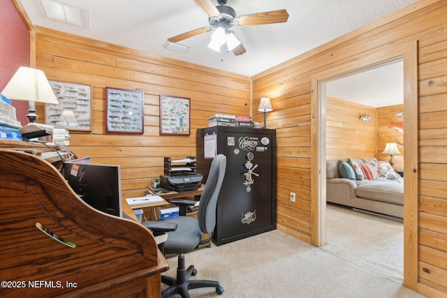 carpeted office space featuring ceiling fan and wooden walls