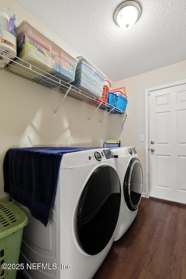 laundry area with dark wood-type flooring, a textured ceiling, and washer and clothes dryer