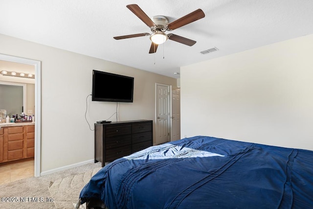 bedroom featuring light colored carpet, ceiling fan, and ensuite bath