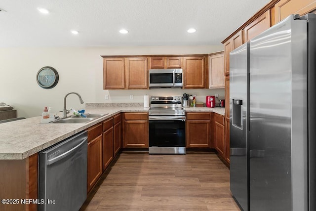 kitchen with appliances with stainless steel finishes, sink, dark wood-type flooring, and kitchen peninsula