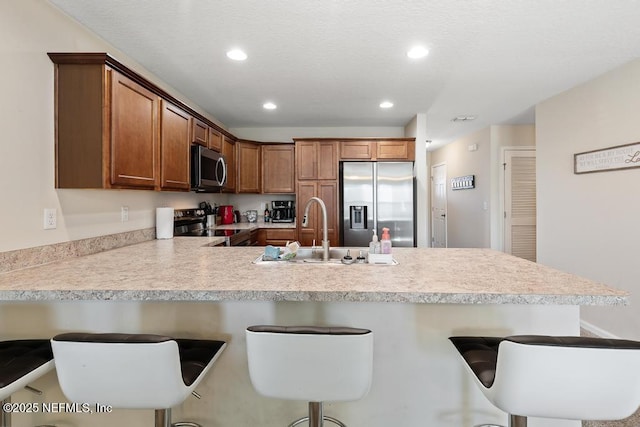 kitchen with appliances with stainless steel finishes, sink, a kitchen breakfast bar, and kitchen peninsula