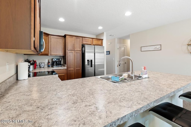 kitchen with stainless steel appliances, a kitchen breakfast bar, kitchen peninsula, and sink