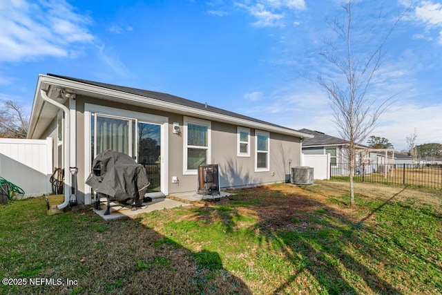 back of property featuring central AC and a lawn