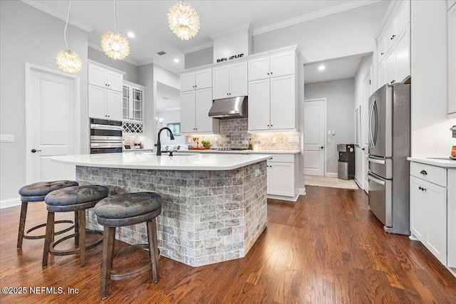 kitchen with sink, decorative light fixtures, stainless steel fridge, an island with sink, and white cabinets