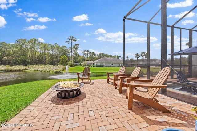 view of patio / terrace with a water view, an outdoor fire pit, and glass enclosure