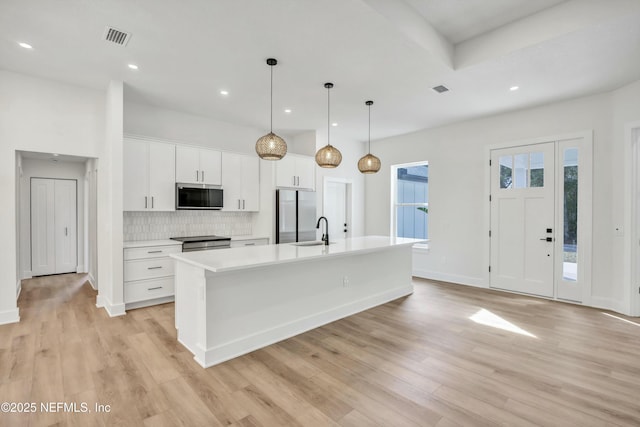 kitchen with white cabinetry, stainless steel appliances, an island with sink, and hanging light fixtures