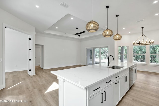 kitchen with stainless steel dishwasher, sink, an island with sink, and white cabinets