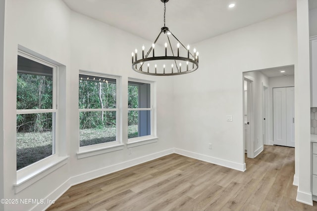 unfurnished dining area featuring a notable chandelier and light hardwood / wood-style flooring