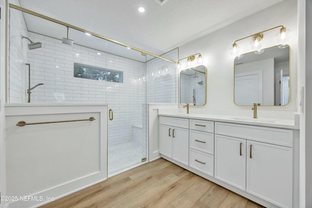 bathroom featuring a shower with door, vanity, hardwood / wood-style floors, and a textured ceiling