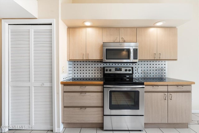 kitchen featuring light brown cabinetry, tasteful backsplash, light tile patterned flooring, and appliances with stainless steel finishes