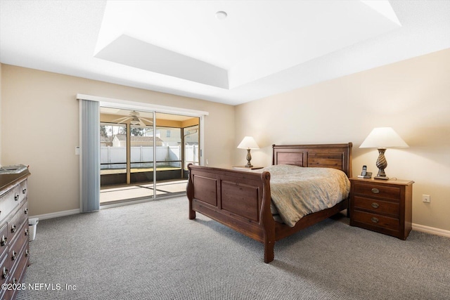 bedroom with access to outside, a raised ceiling, and carpet