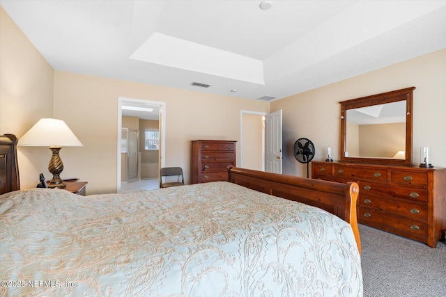 carpeted bedroom with a raised ceiling and ensuite bathroom