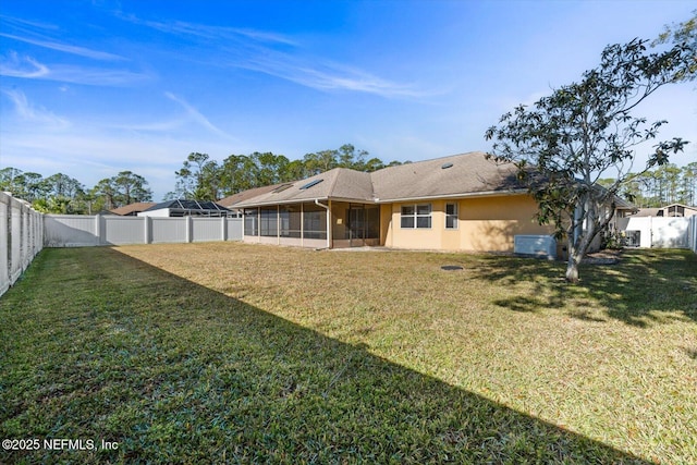 rear view of house featuring a sunroom and a lawn