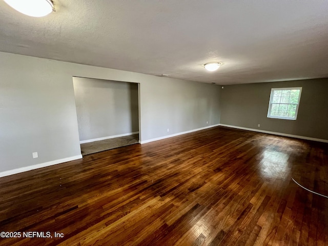 unfurnished room featuring dark hardwood / wood-style flooring and a textured ceiling