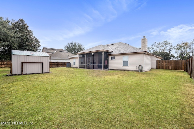 rear view of property featuring a storage unit, a sunroom, and a lawn