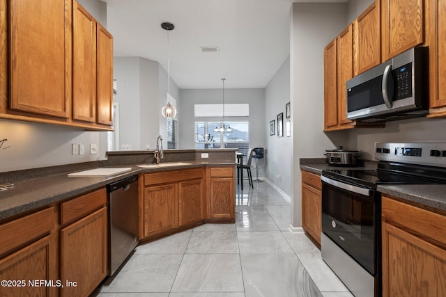 kitchen with sink, hanging light fixtures, stainless steel appliances, kitchen peninsula, and a chandelier