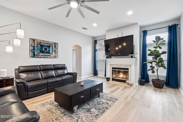 living room featuring a fireplace, light hardwood / wood-style floors, and ceiling fan