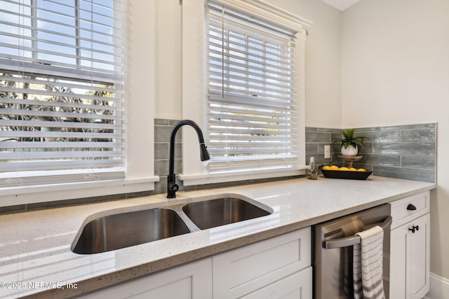 kitchen with white cabinetry, sink, stainless steel dishwasher, and light stone counters