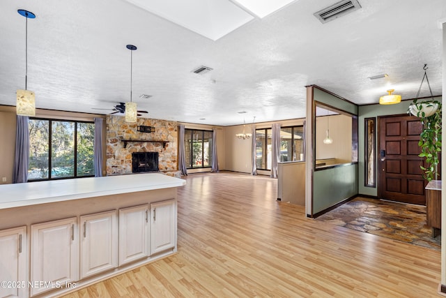 kitchen featuring a stone fireplace, pendant lighting, ceiling fan, and light hardwood / wood-style floors